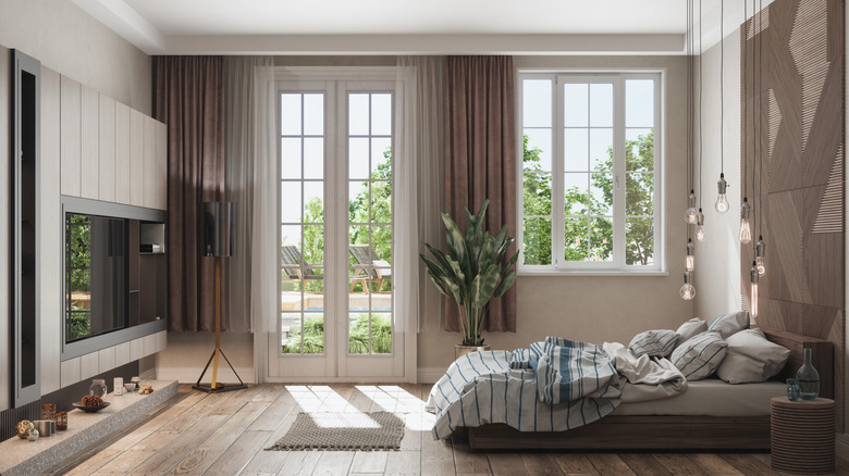 A bright room with French doors and a large window with a large television on the wall.
