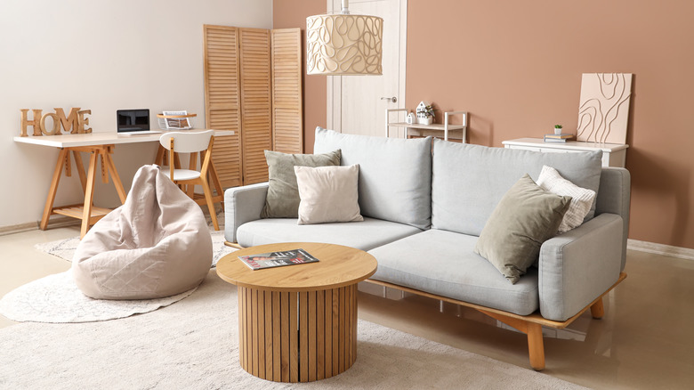 A modern living room in white and beige tones with a white bean bag chair matching the couch