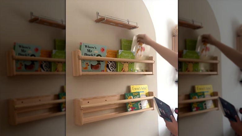 Hands putting children's books in shelves on taupe arch