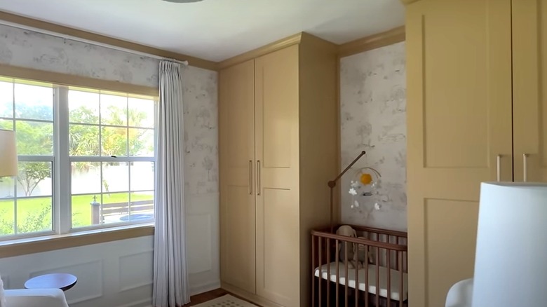 A wooden crib sits between two yellow cabinets in nursery