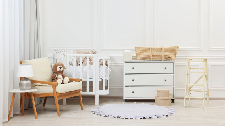 A monochromatic white nursery features an accent wall with decorative molding