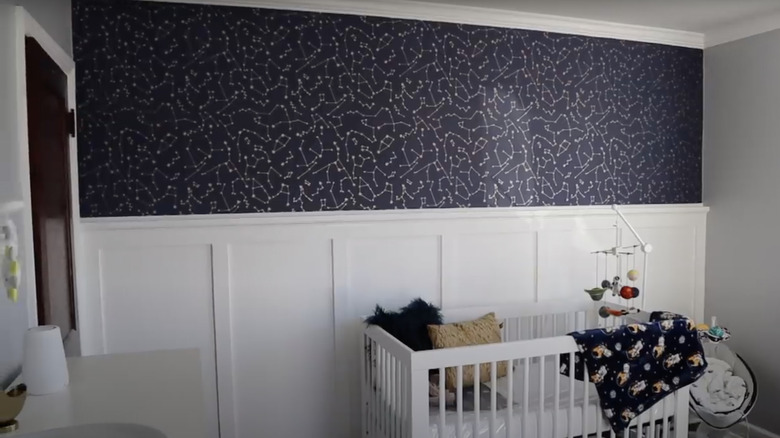 A celestial print wallpaper is installed above board and batten in a baby's nursery
