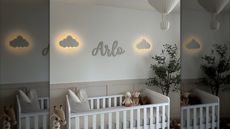 A wall plaque with the name "Arlo" is flanked by two illuminated cloud nightlights above a white crib