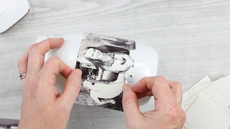 Someone adding a black and white picture to the side of a mason jar