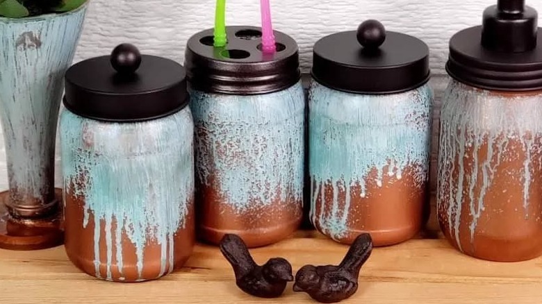 Four mason jars with different lids and uses covered with copper paint and patina