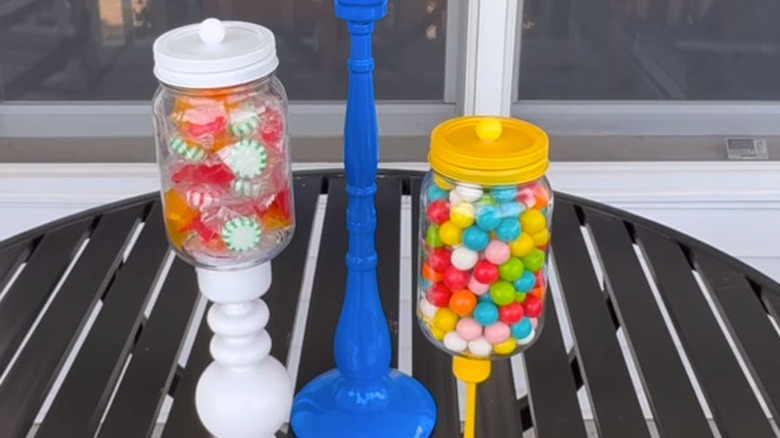 White, blue, and yellow candle stands with clear mason jars full of candy on top