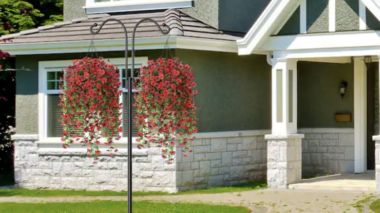 Two faux flower hanging baskets hanging in front of a home
