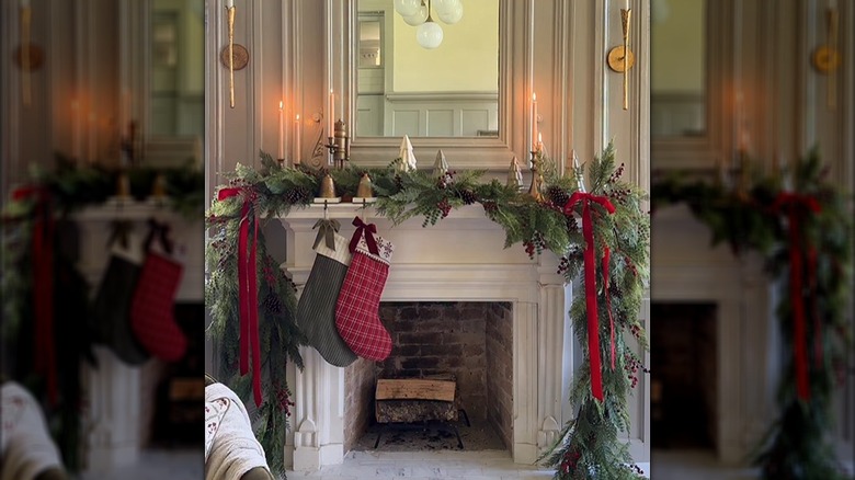 A colonial-style fireplace is decorated traditionally with evergreens, and green and red accents.