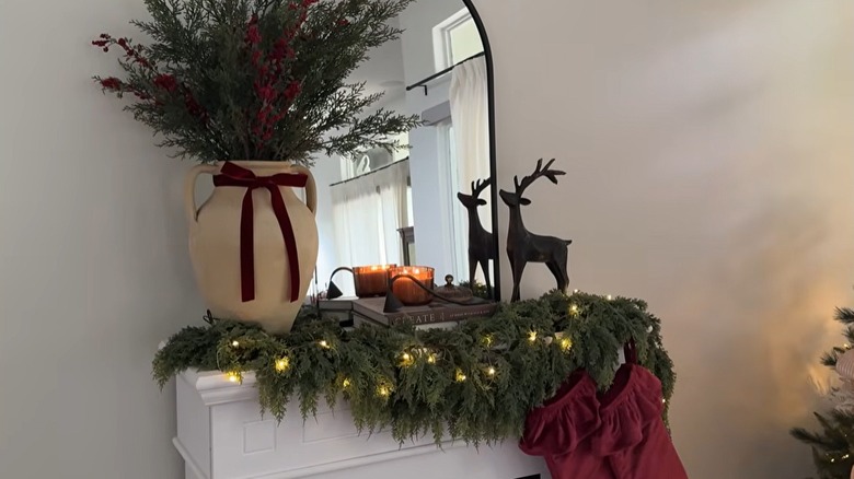 An asymmetrical holiday mantel display has burgundy accents.