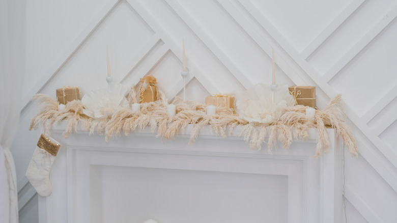 White and cream-colored holiday decorations sit on a white mantel.