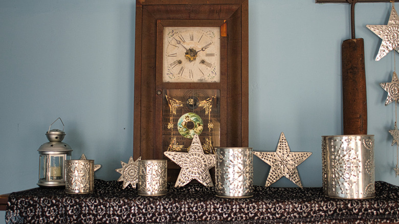 Punched tin lanterns and a clock decorate a mantel.