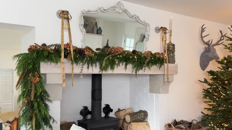 Pinecones, dried flowers, and greenery decorate a stone mantel.