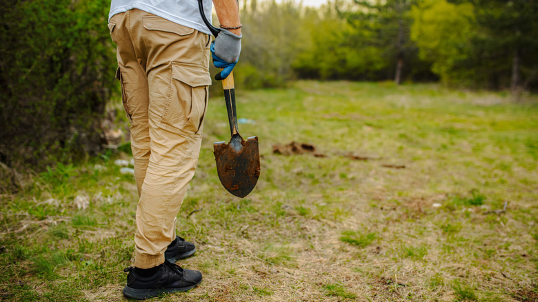Man standing with shovel in hand looking at backyard