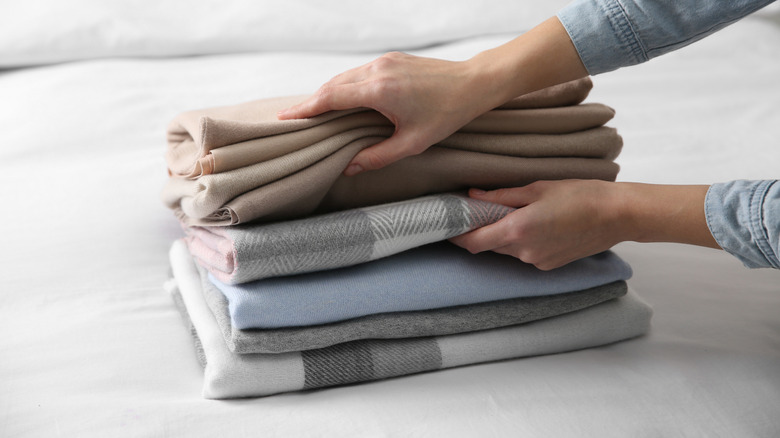 Woman picking up a pile of blankets