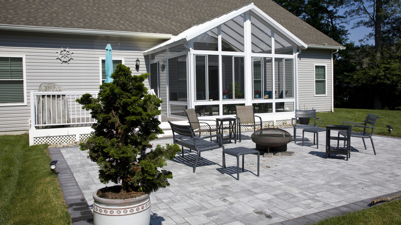 An exposed paved backyard patio with a firepit and chairs.