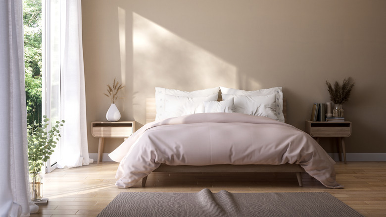 modern light bedroom with neutral tones, king sized bed, two night stands and large open window