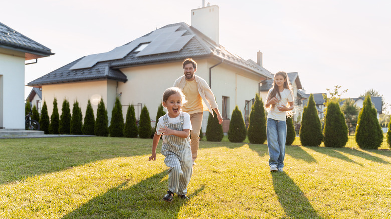 Family playing in the yard of a house with solar panels