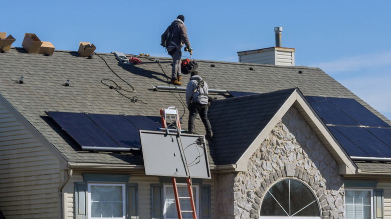 Workers installing solar panels on a home's roof