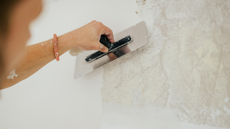 person using skim coating to cover wall texture