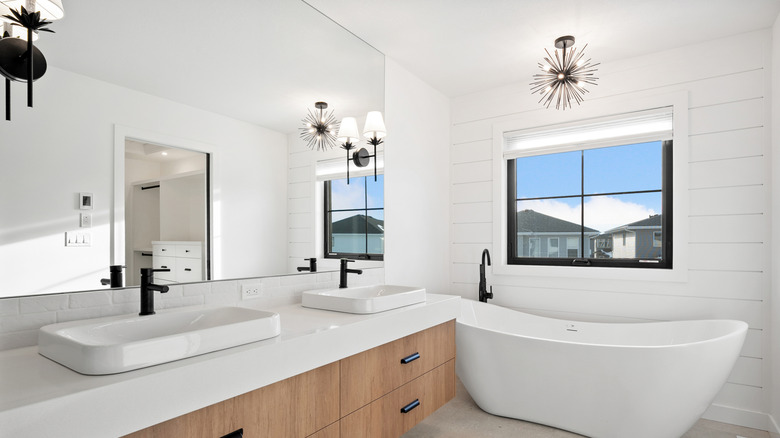A white bathroom with multiple lights on the wall and ceiling