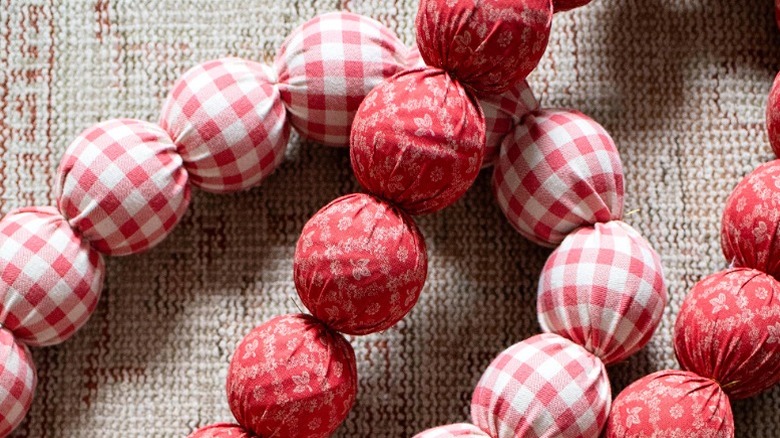 Two red and white garlands are made from cloth and ball ornaments.