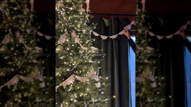 A Christmas tree and window are decorated with garland made from a tablecloth.