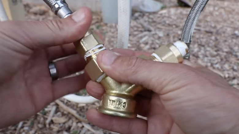 person connecting waterline to faucet