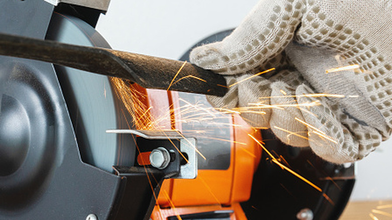Sharpening a lawn mower blade on a bench grinder