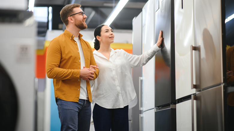 A couple looking at refrigerators at an appliance store