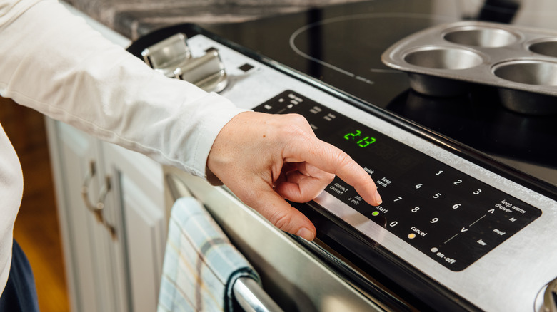 A man's finger setting oven temperature in a kitchen
