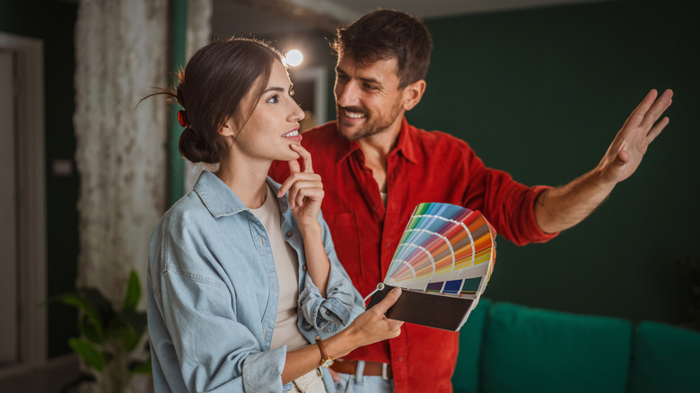 A couple selecting a paint color from a sample booklet