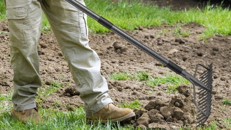 A person using Diig's 49-inch Bow Rake on soil