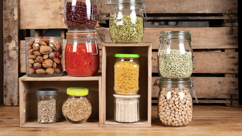 Jars of nuts and legumes in front of a wooden crate.
