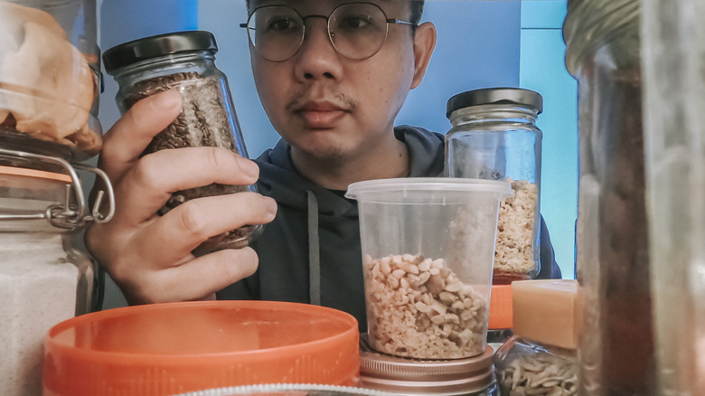 point of view Asian man retrieving food bottle from shelf cabinet at kitchen