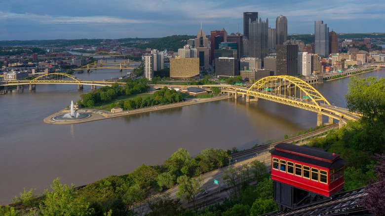 Cityscape of Pittsburgh with yellow bridges over rivers.