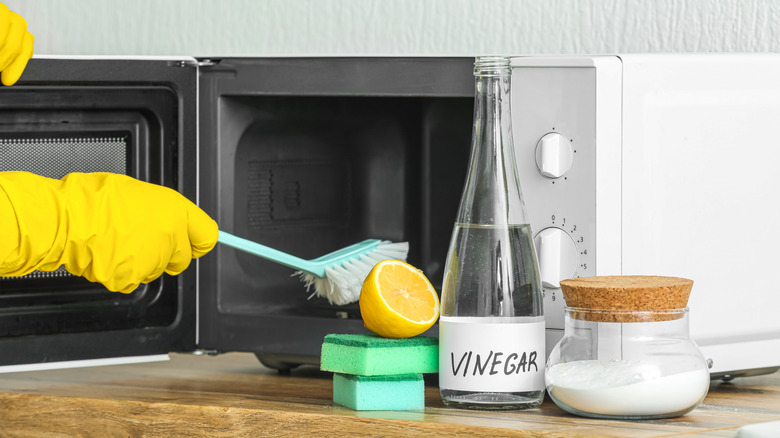 gloved hand cleaning microwave
