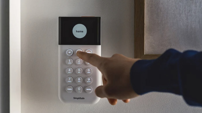Hand touching the keypad for the SimpliSafe security system