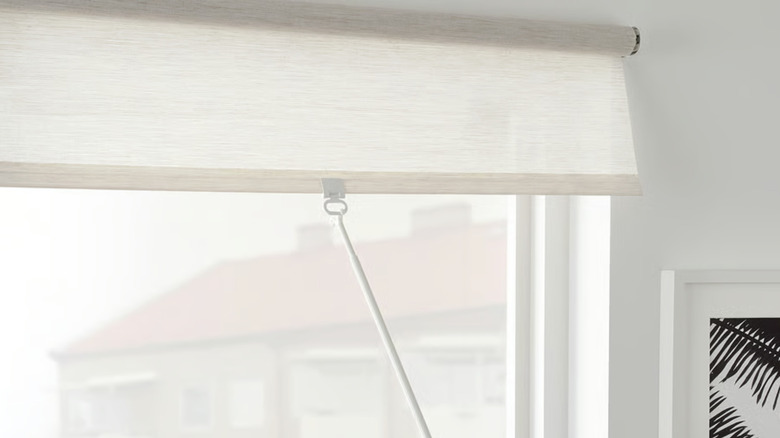 The SANDVEDEL roller blind from IKEA being pulled down on a window in a white room