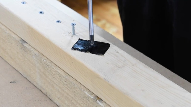 person removing screw with duct tape