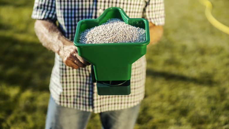 A man holding a bucket of fertilizer
