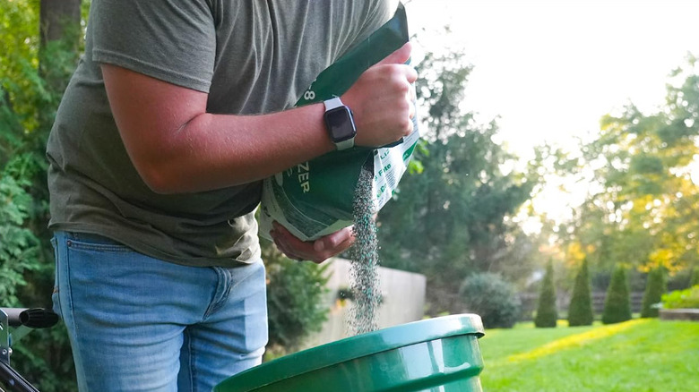 A person pouring Andersons fertilizer into a spreader