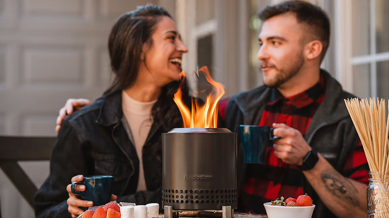 A couple relaxing outside their home with Solo Stove's 9-inch Mesa XL Fire Pit
