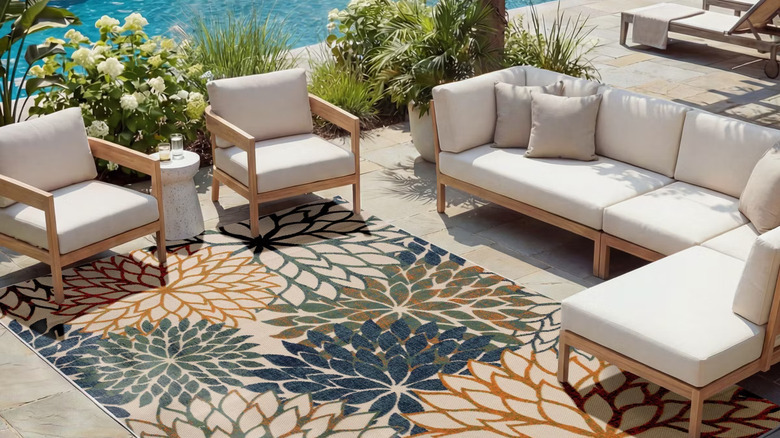 Nourison's Aloha Floral Bloom Flatweave Area Rug on a poolside patio.