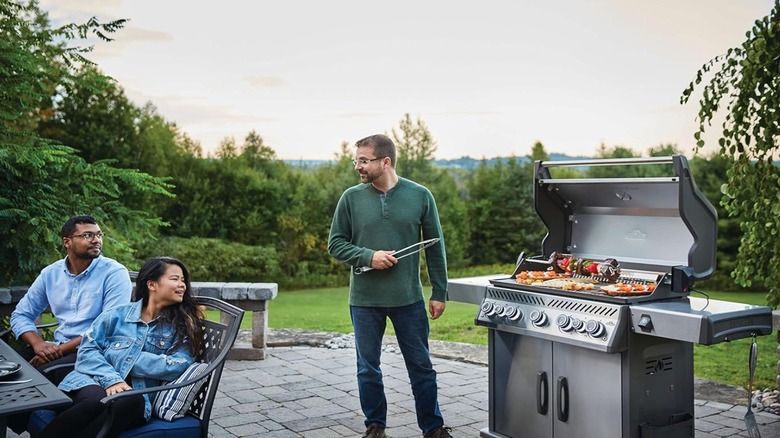 A man cooking on a large stainless steel Napoleon grill