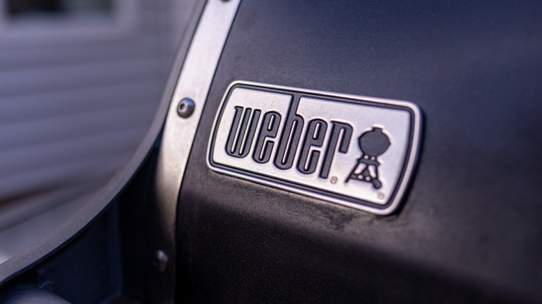 A close-up of a metal Weber grill logo