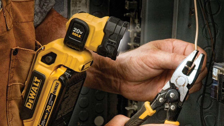 An electrician uses a DeWalt clip on light to illuminate his pliers and wire