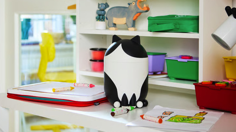 Cat-shaped storage bin sitting on a child's desk with crayons and coloring supplies