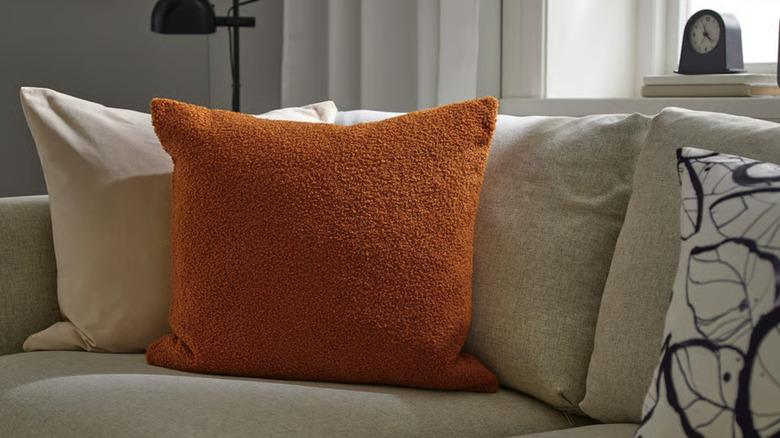 Throw pillows on a couch with a clock in the background