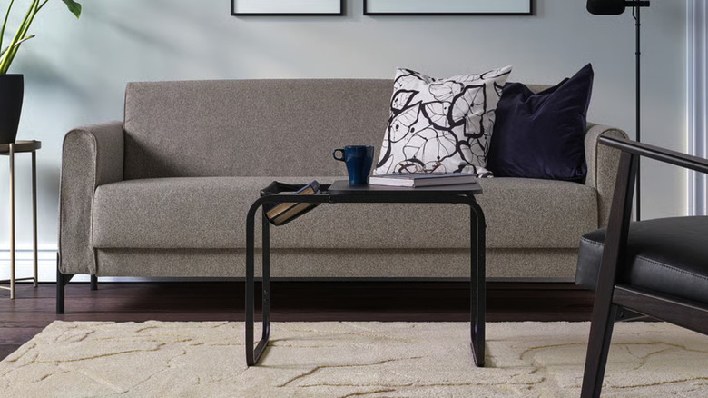 Beige PELARKÖRSBÄR rug in a living room with a small couch, coffee table, and black chair
