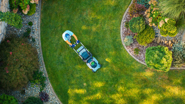 A top-down view of a person mowing a lawn
